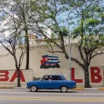 red sedan on road near trees during daytime