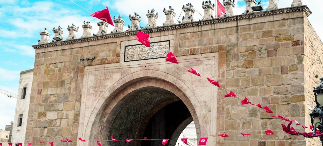 a stone gate with a red kite flying in the air